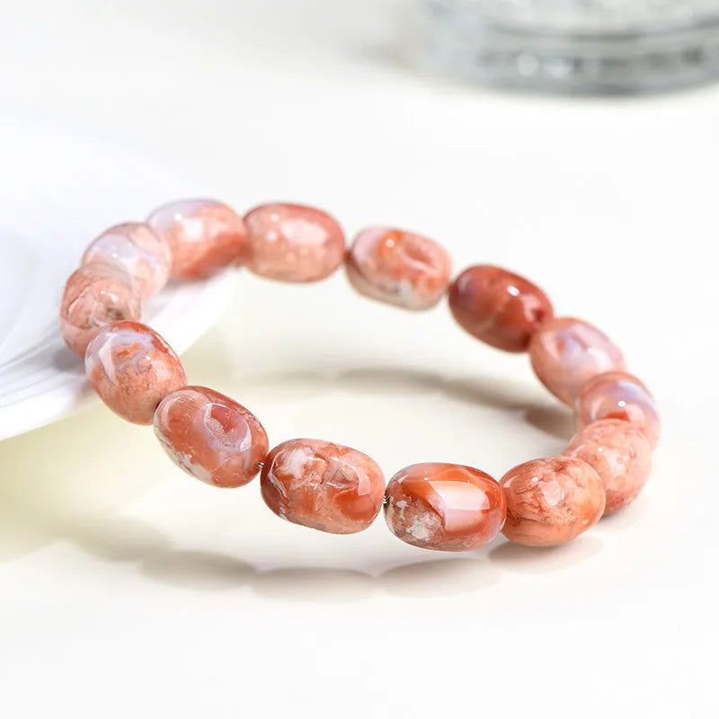 Natural cherry agate barrel bead bracelet with Ruyi charm on a white background.