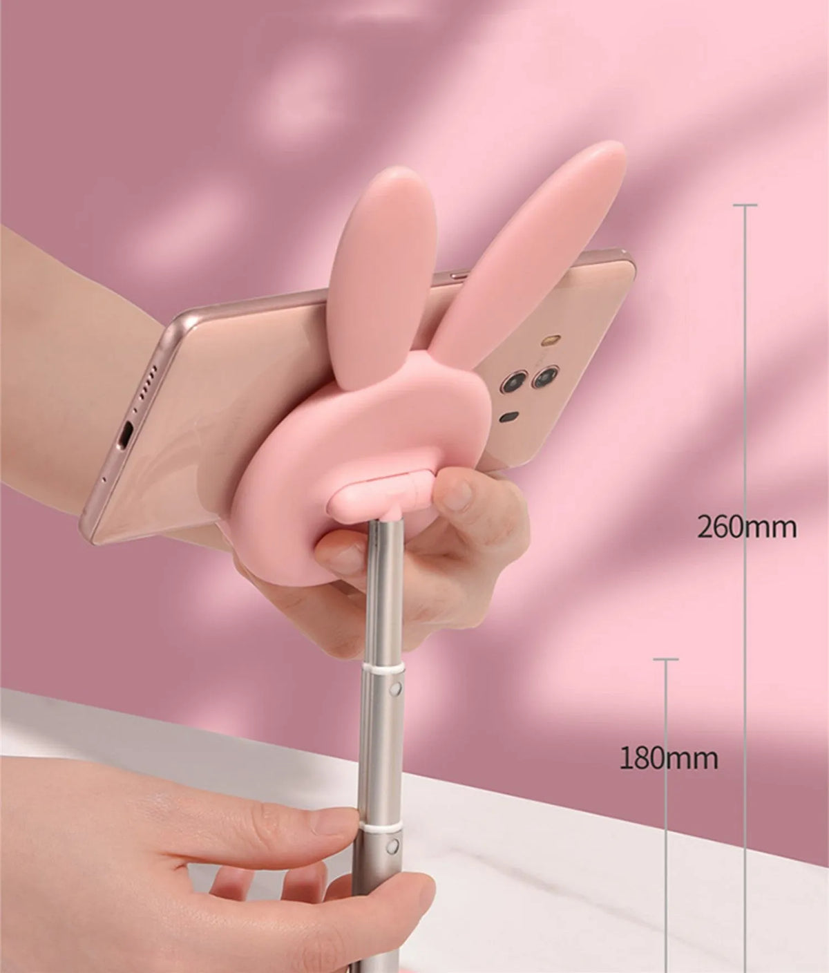 Rabbit-shaped silicone phone stand in pink on a desk with a smartphone placed in it