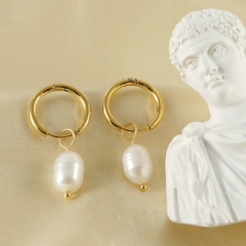 A pair of gold geometric earrings with pearl details on stainless steel and titanium steel posts.