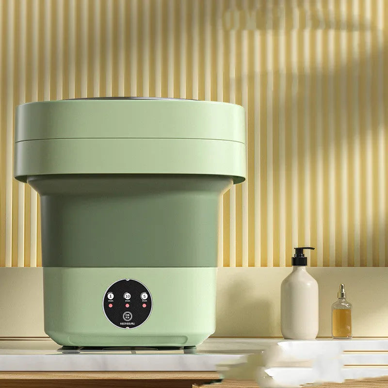Green foldable mini portable washing machine with drain pipe and basket on a white background.