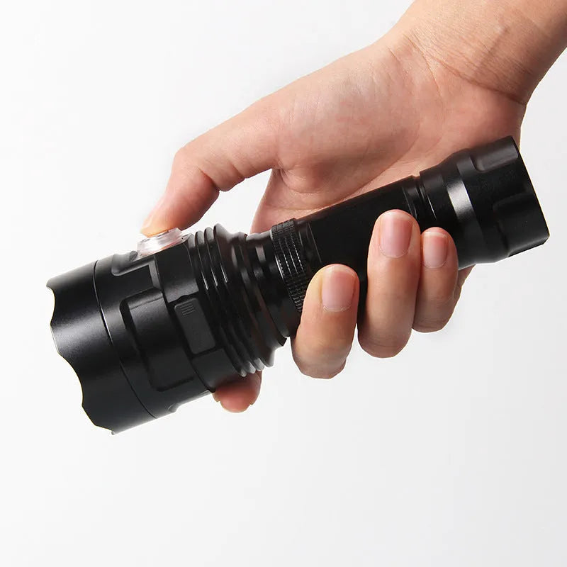 Black aluminium XHP90 LED tactical flashlight showing scale next to USB cable and yellow packaging box.