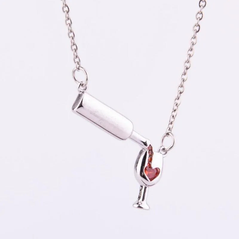 Gold alloy wine bottle and glass pendant necklace on a light background