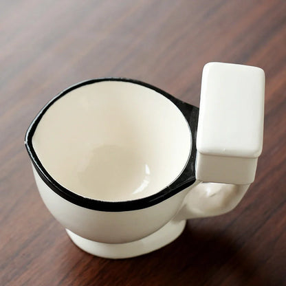 Humorous toilet-shaped ceramic coffee mug with handgrip, perfect for gag gifts or unique decor