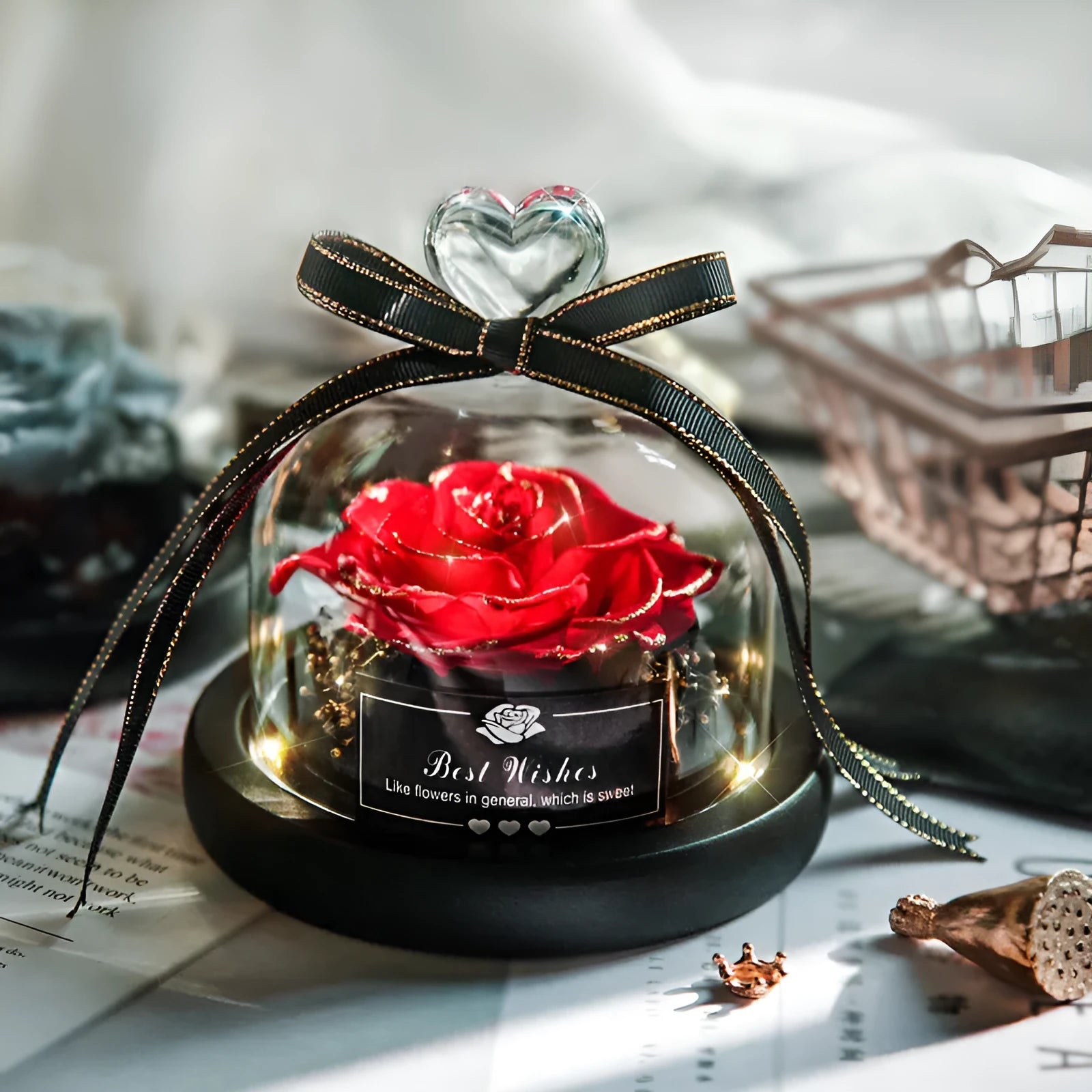 Eternal preserved red rose illuminated by LED light inside a clear glass dome on a wooden table.