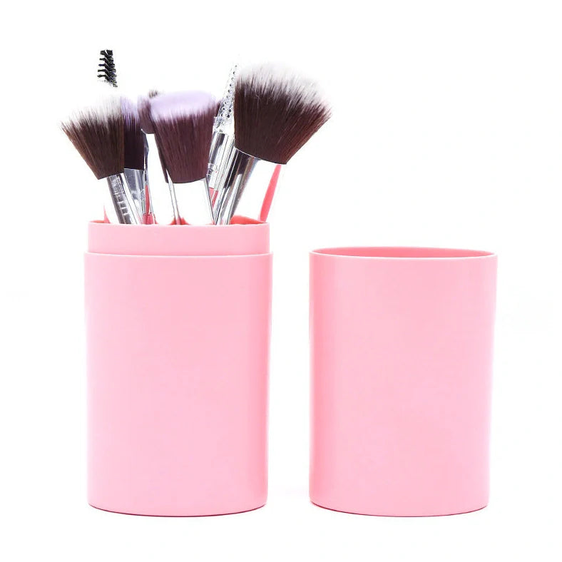 12 makeup brushes with pink handles and black bristles arranged in white storage bucket