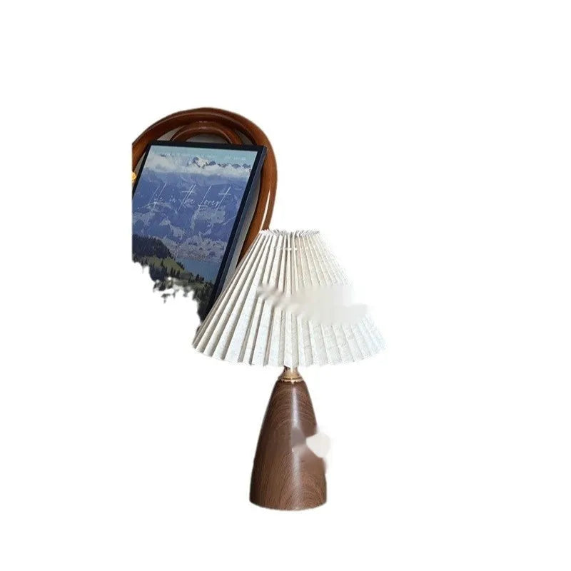 Tapered floral ceramic table lamp with remote control on a wooden surface.