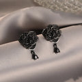 Close-up of women's black rose zircon flower stud earrings with 18K gold plating.