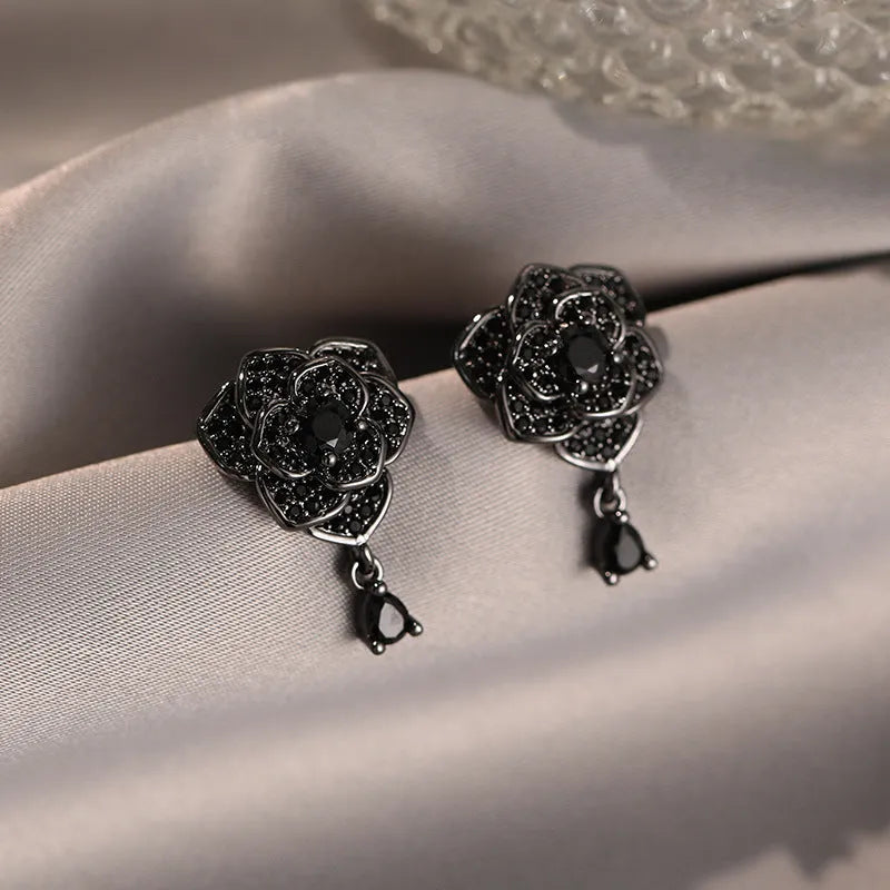 Close-up of women's black rose zircon flower stud earrings with 18K gold plating.