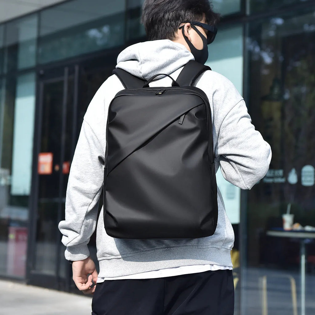 Men's large black waterproof PU backpack showing sewing thread detail and separate computer bag.