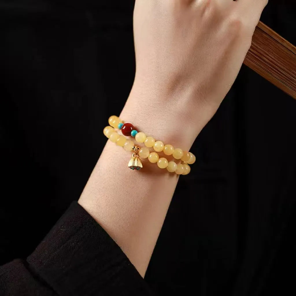Yellow jade double ring bracelet with topaz lotus seedpod design on white background