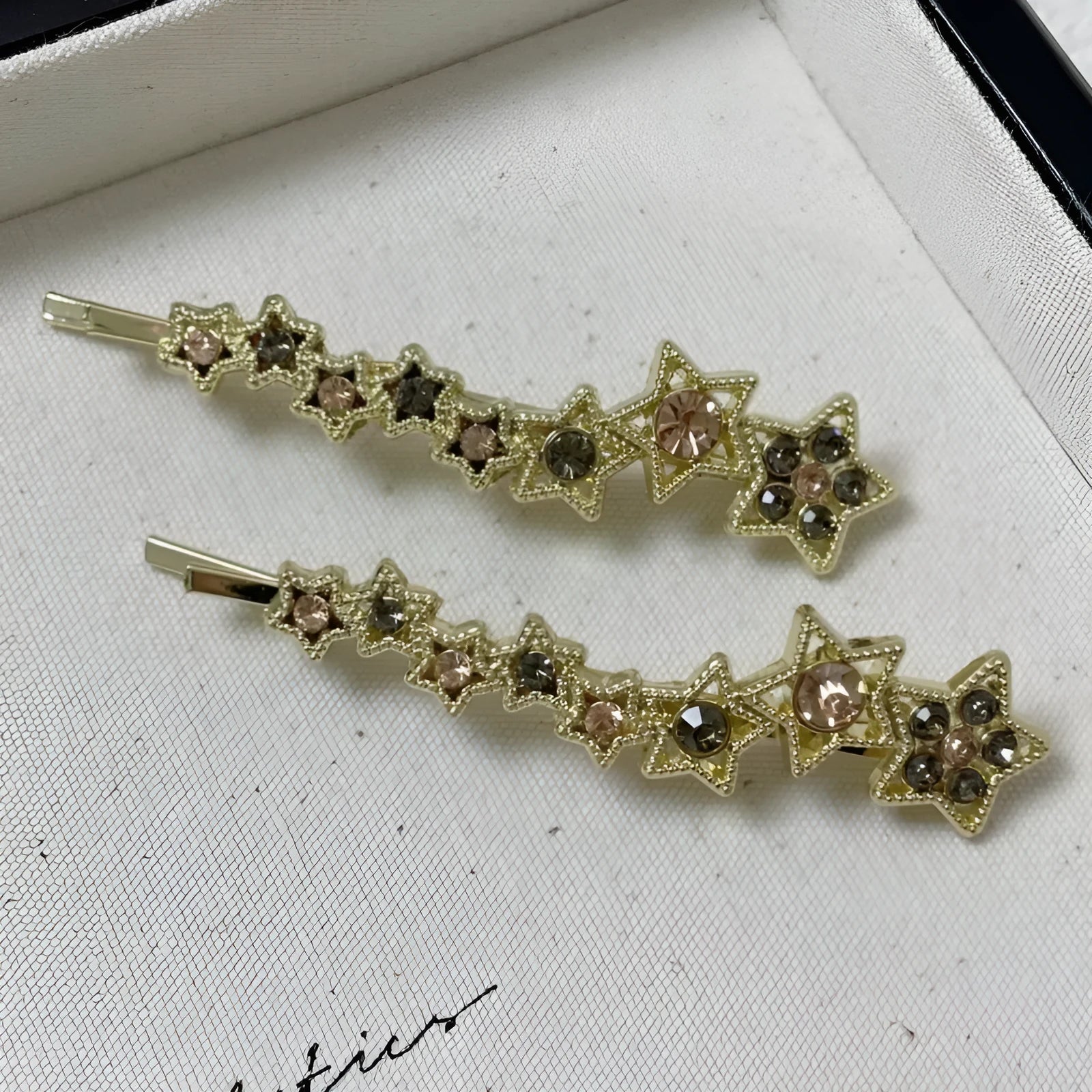Gold alloy rhinestone barrette with a side clip, star decoration, and text.