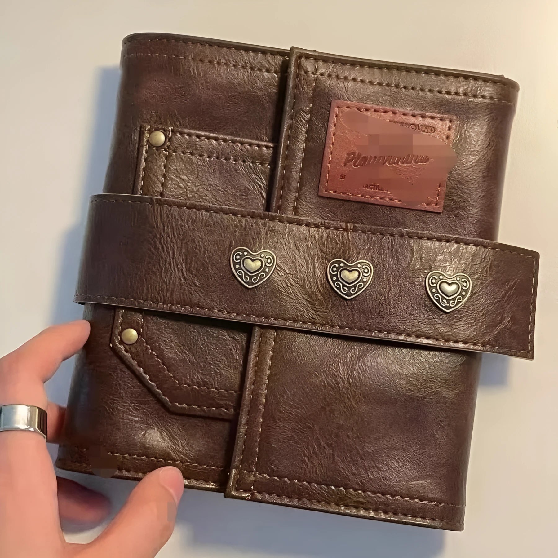 Brown A7 notebook with a leather buckle closure on a PU cover, showing loose-leaf binding