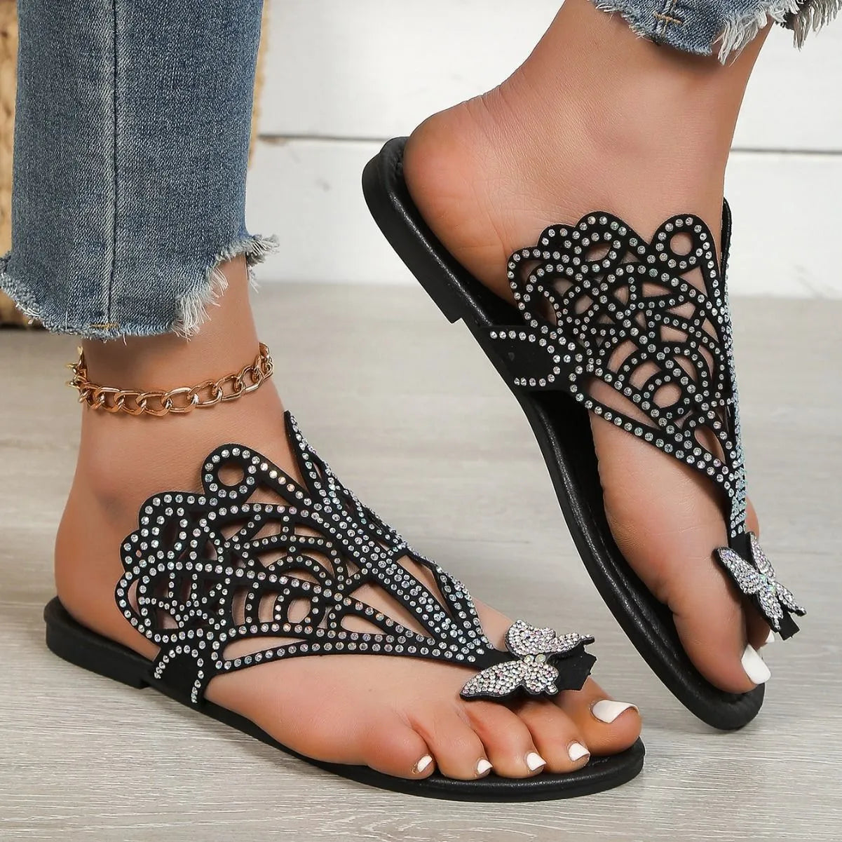 Women's black slip-on sandals with rhinestone decoration and a flip-toe design on a light background.