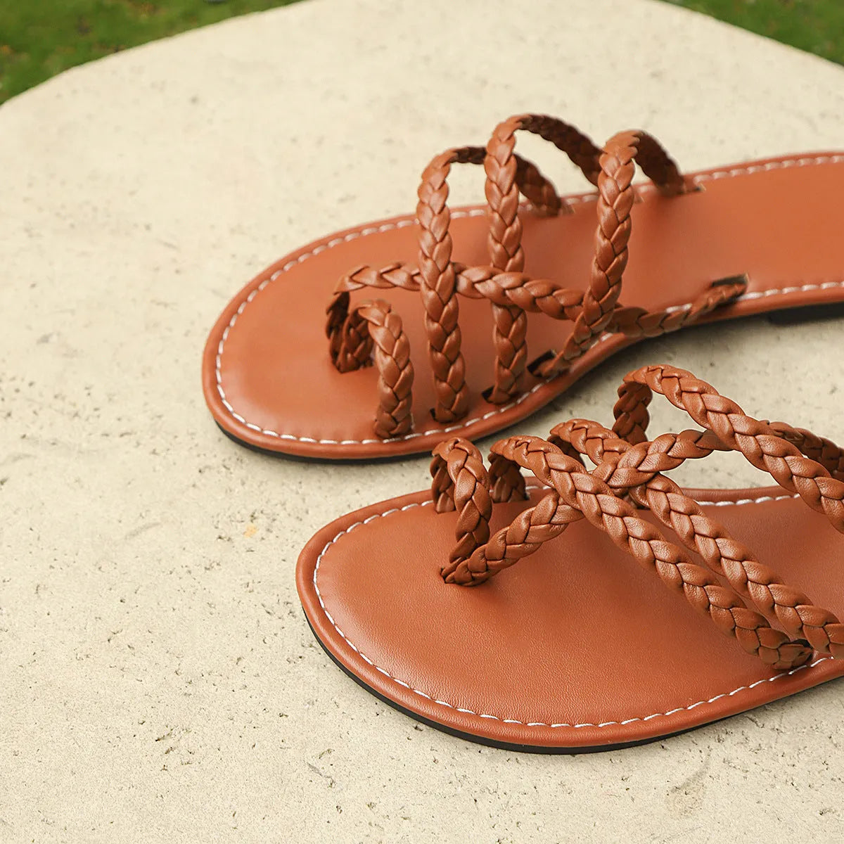 Women's black woven clip-toe flat sandals on a neutral background.