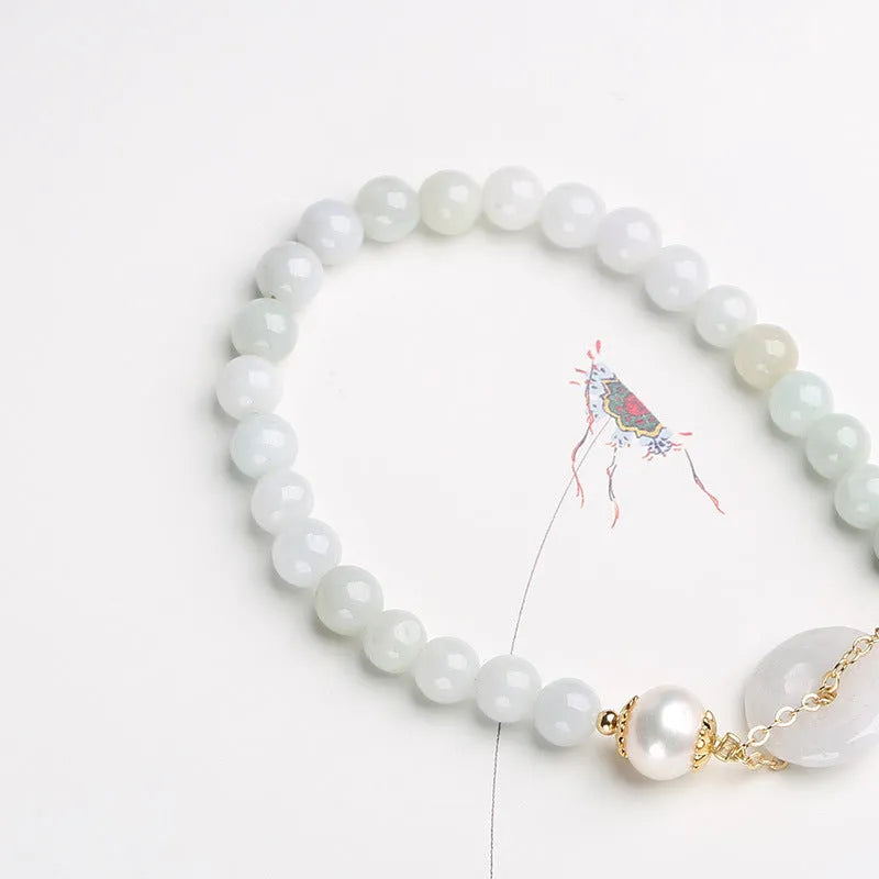 Jade and pearl bracelet with geometric pendant and peace buckle charm on wrist