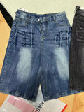 Man wearing loose straight-leg washed denim shorts in blue, showing cropped length and casual style.