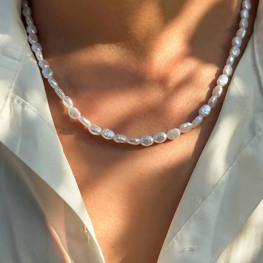 Men's white U-shaped pearl necklace with mother-of-pearl pendant on a pearl chain.