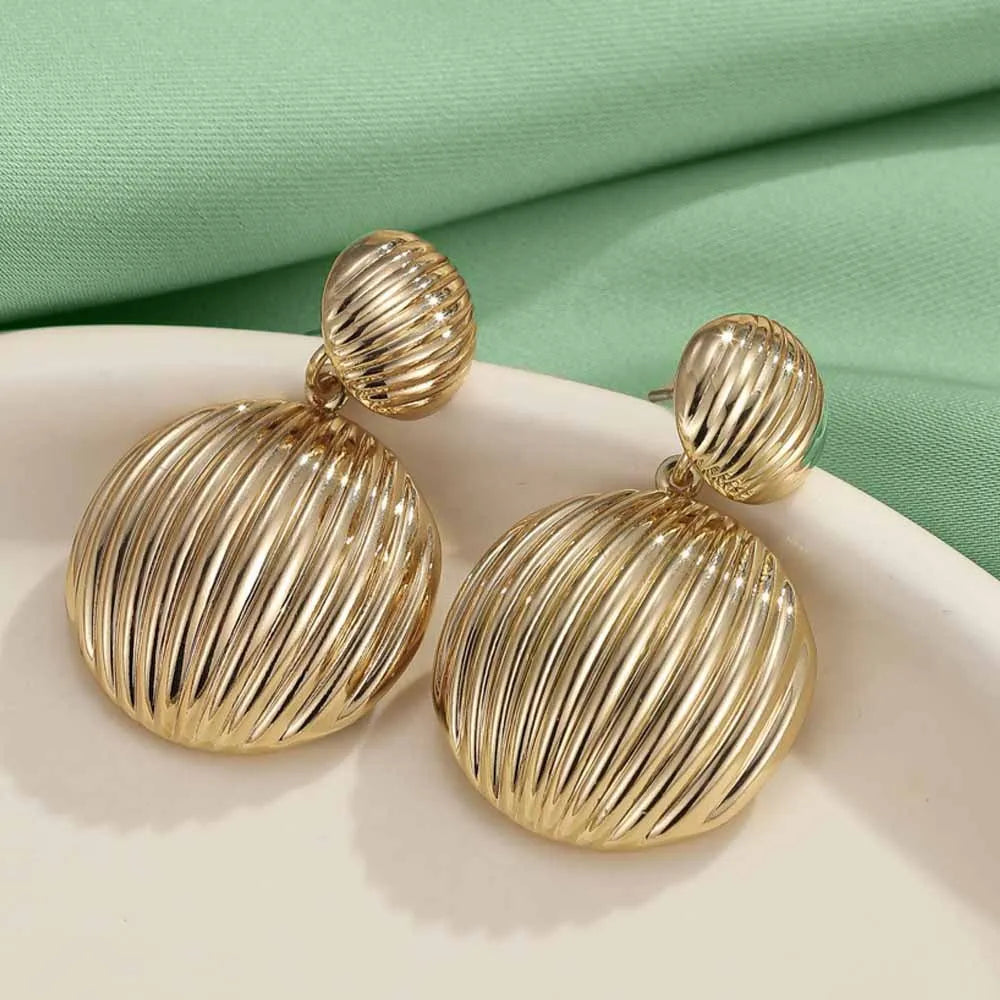 Gold alloy heart-shaped and round earrings for women on a plain background