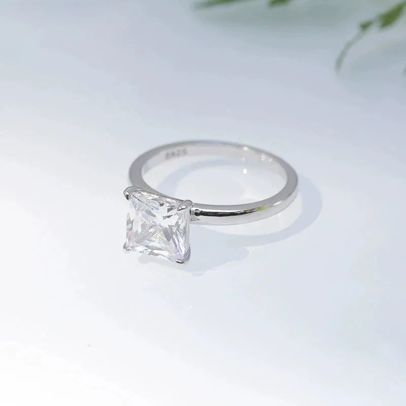 A polished geometric sterling silver ring for women on a grey background.