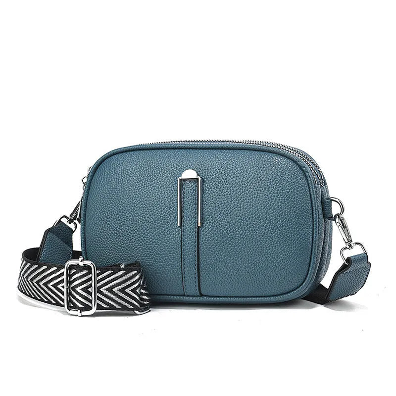 A soft oval-shaped women's crossbody bag in PU leather with a stone pattern texture and a front slit pocket.