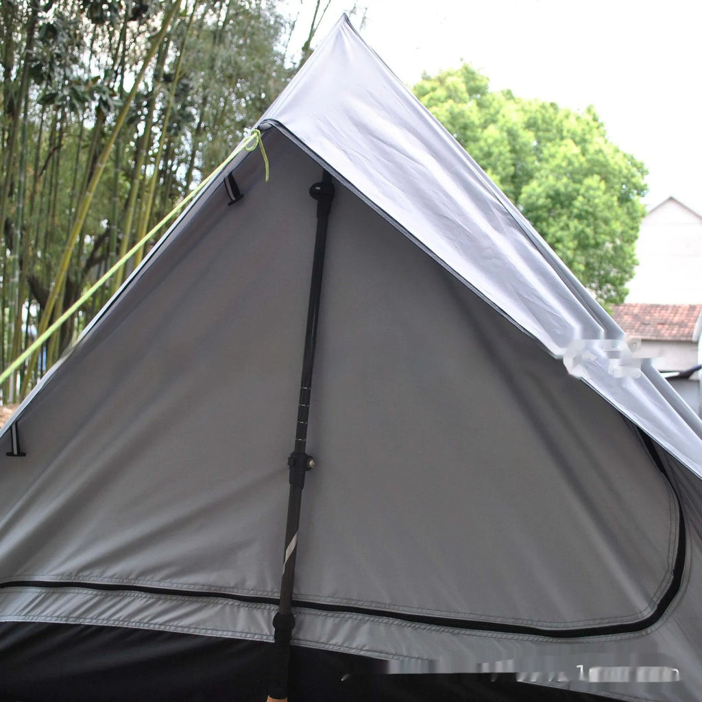 Lightweight brown A-line hiking tent set up with hiking cane supports in outdoor setting