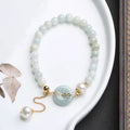 Jade and pearl bracelet with geometric pendant and peace buckle charm on wrist