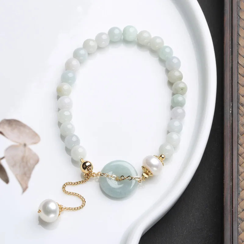 Jade and pearl bracelet with geometric pendant and peace buckle charm on wrist