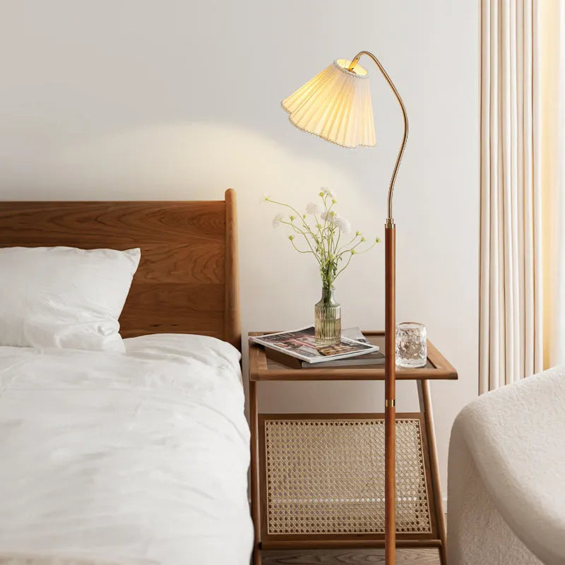 Solid wood floor lamp with fabric shade in walnut colour placed beside a sofa in a living room
