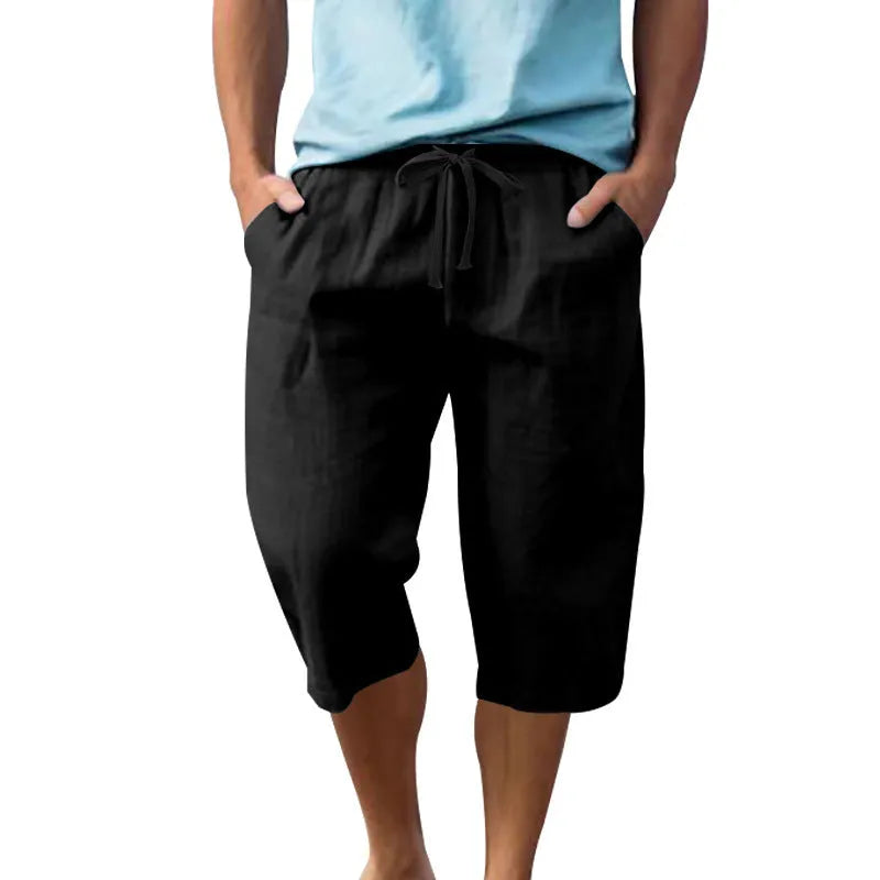 Man wearing loose, cropped linen shorts in a solid colour with a drawstring waist.