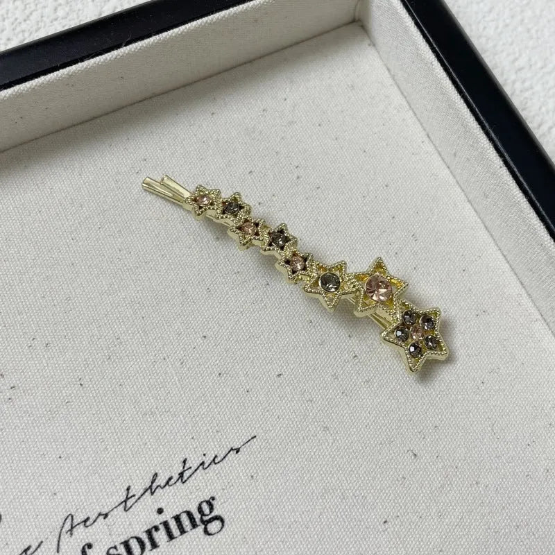 Gold alloy rhinestone barrette with a side clip, star decoration, and text.