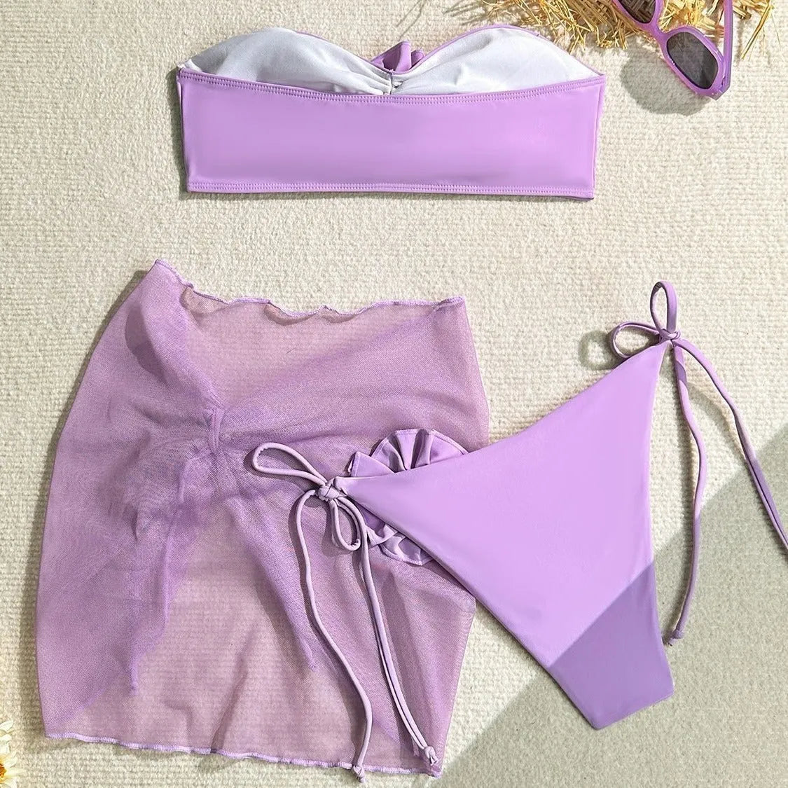 Women's pink swimsuit set with a large tied flower on the tube top, matching pants, and a skirt.