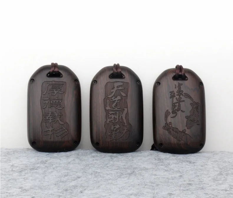 Solid ebony sandalwood key case with key rings, showing carved wood grain on a plain background