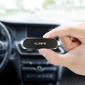 Black magnetic car phone holder with silver iron plate and white adhesive, shown next to a mobile phone.