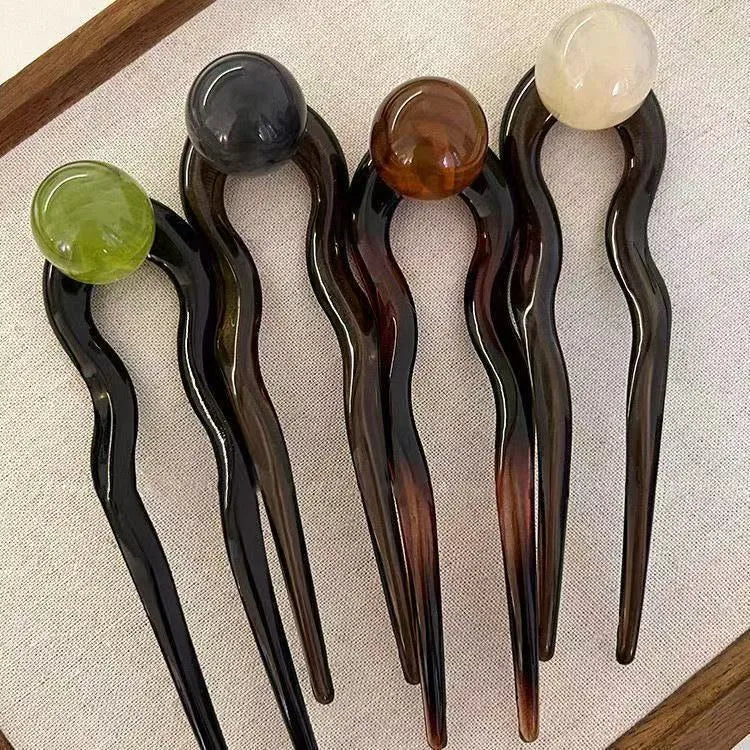 A set of simple U-shaped acrylic hair barrettes with a retro ball detail in beige and caramel colours.