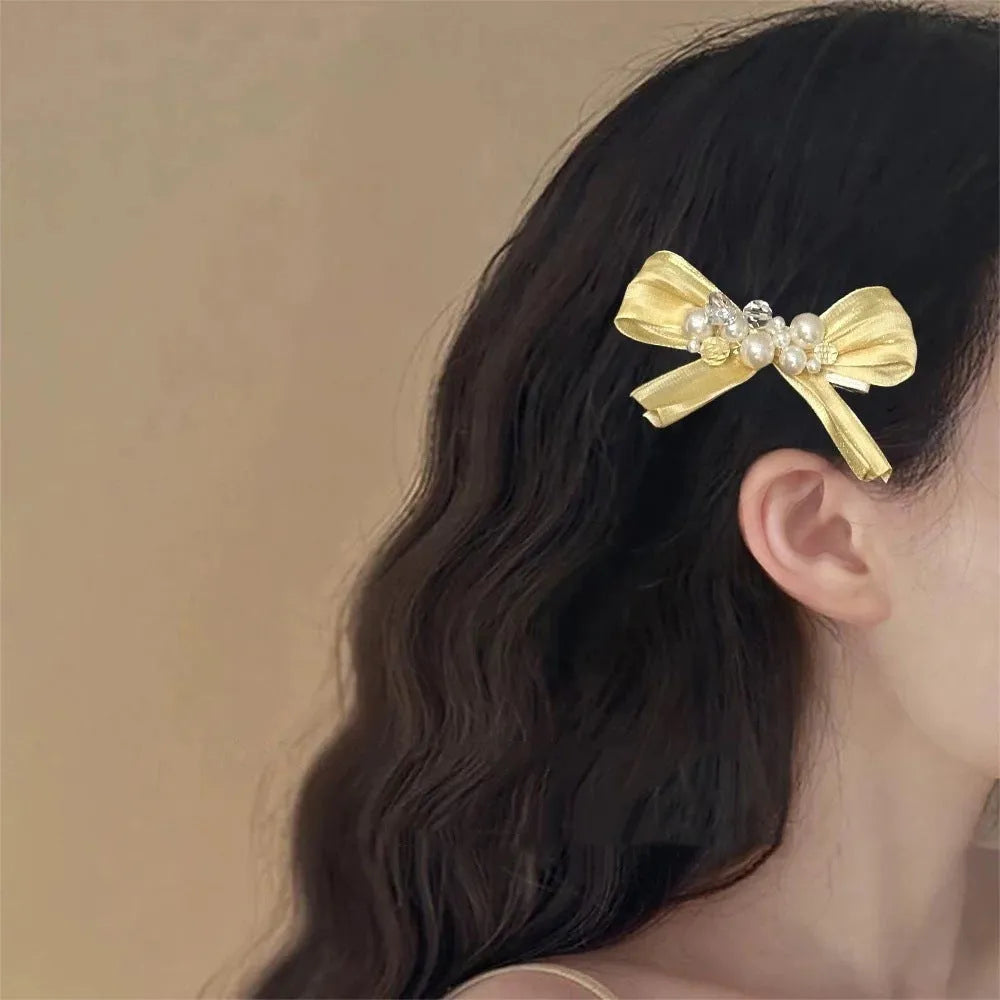 Yellow bow hair barrette with rhinestone pearl detailing and duckbill clip design