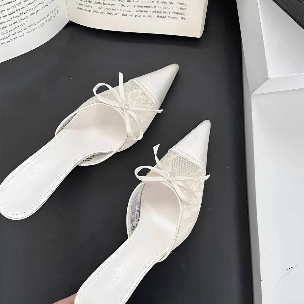 Women's light brown lace high heels with a pointed toe and a black bowknot detail on the front.