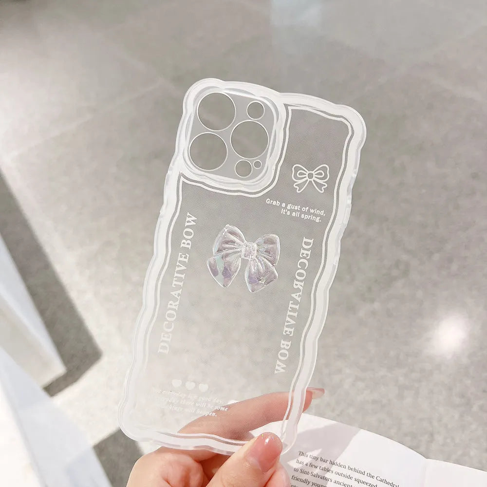 Clear iPhone case with a raised 3D bow design on the back, shown next to a white love lanyard.