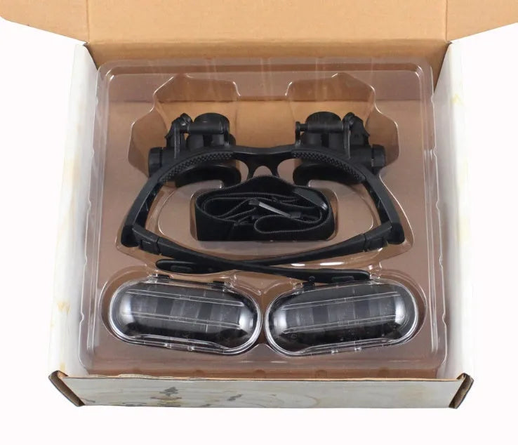 Double eye LED magnifier glasses with headband and 4 interchangeable lenses on black background