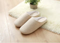 Men's black cotton indoor slippers with soft anti-skid sole on a wooden floor