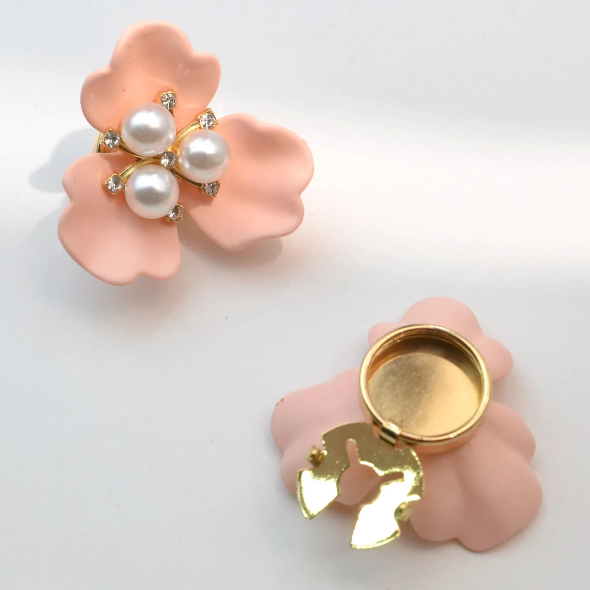Metal cufflinks with pearl three-flap design in gold, pink, red, and white colours on white background