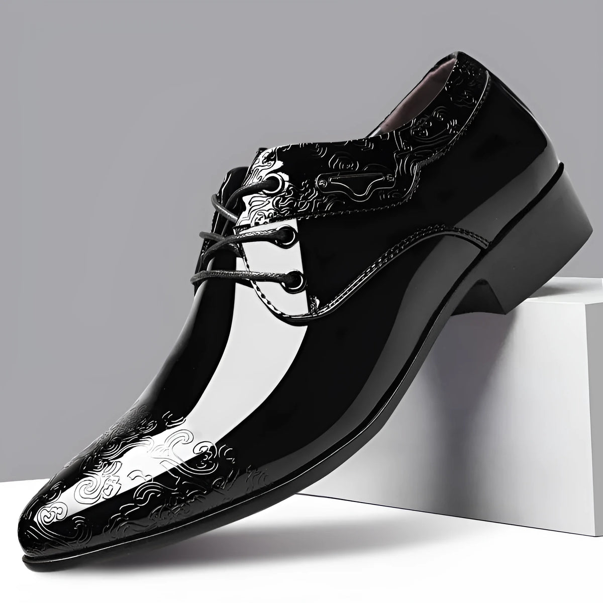 Glossy black men's formal shoes with pointed toe, low top, and carved detail on microfiber leather upper