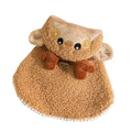 Cat wearing a green granular velvet Christmas cape with a star-topped tree hat, standing on a wooden floor