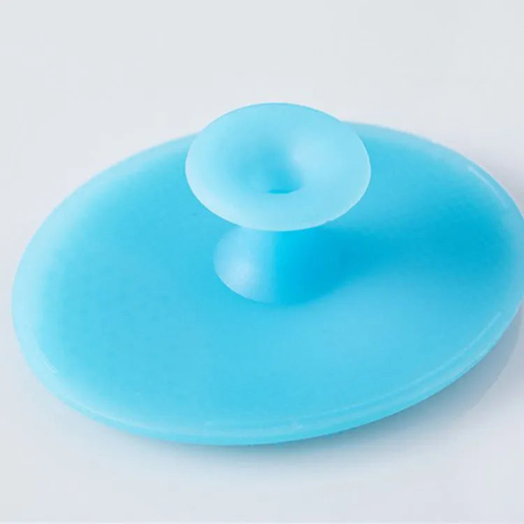 Silicone facial brush in three bristle zones with suction cup on blue background