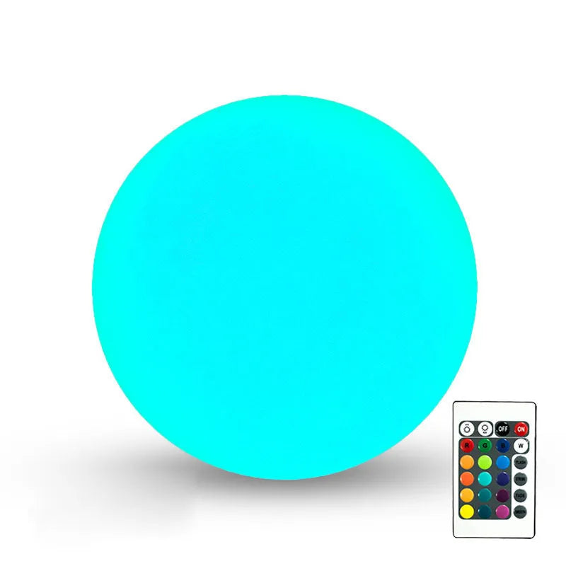 Spherical blue LED garden floor lamp with remote control sitting on grass.