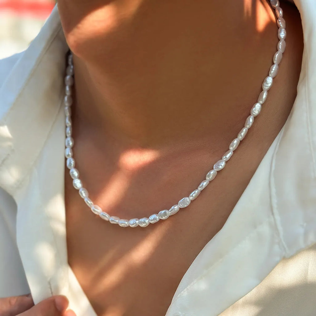 Men's white U-shaped pearl necklace with mother-of-pearl pendant on a pearl chain.