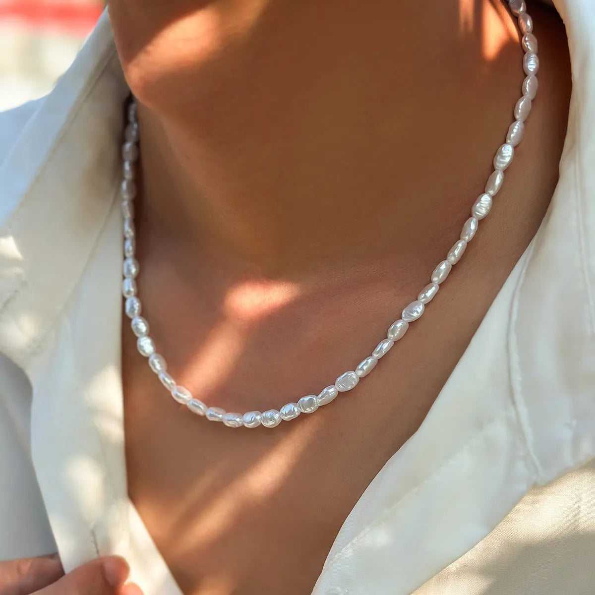 Men's white U-shaped pearl necklace with mother-of-pearl pendant on a pearl chain.