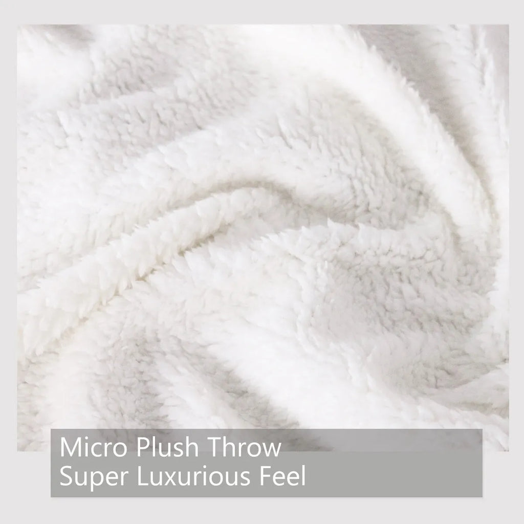Black sherpa fleece blanket folded on a couch, soft fabric with hemmed edges.