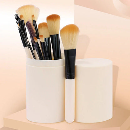 12 makeup brushes with pink handles and black bristles arranged in white storage bucket