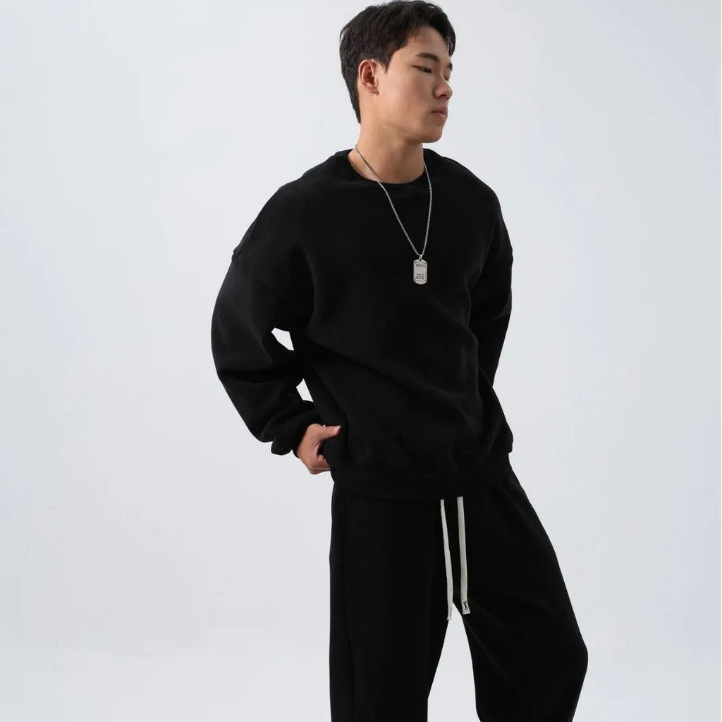 Men's black polar fleece sports suit with crew neck jacket and loose fit trousers laid flat.