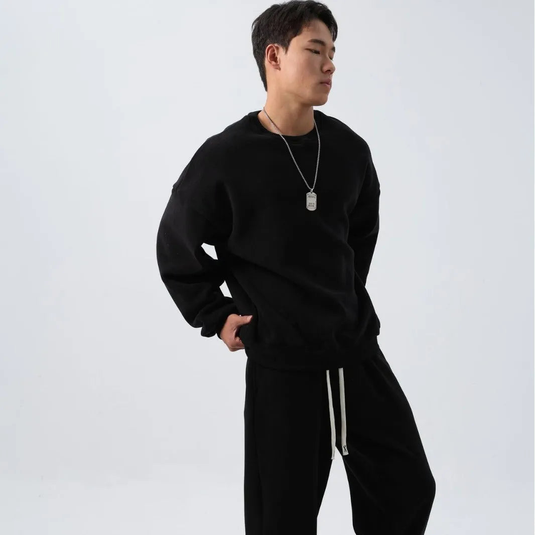 Men's black polar fleece sports suit with crew neck jacket and loose fit trousers laid flat.